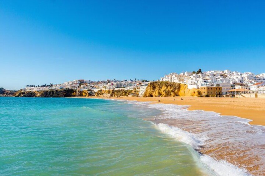 En kystby med hvide bygninger, en sandstrand og turkisblåt vand. 2