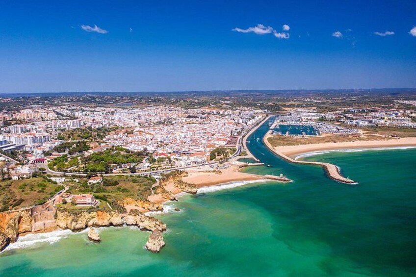 A coastal city with a beach, a marina, and a rocky coastline. 3