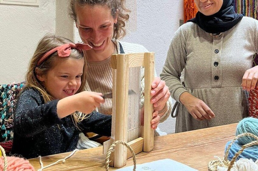 Iemand houdt een houten lijst vast, mogelijk een fotolijst, terwijl een kind en een andere persoon in de buurt staan. 4