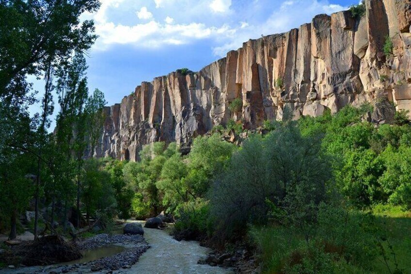 A river flowing through a canyon with rocky cliffs and dense greenery. 1