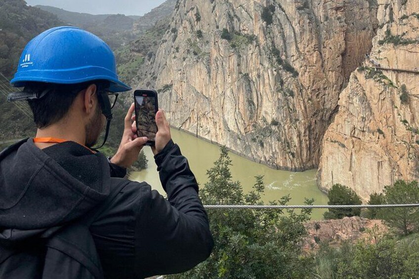 A person taking a photo of a canyon with a river. 3