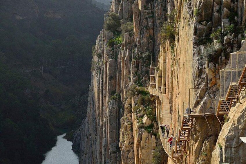A steep rock face with a narrow path and wooden stairs. 2