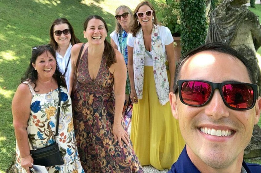 A group of people outdoors, a statue, and a grassy area. 2
