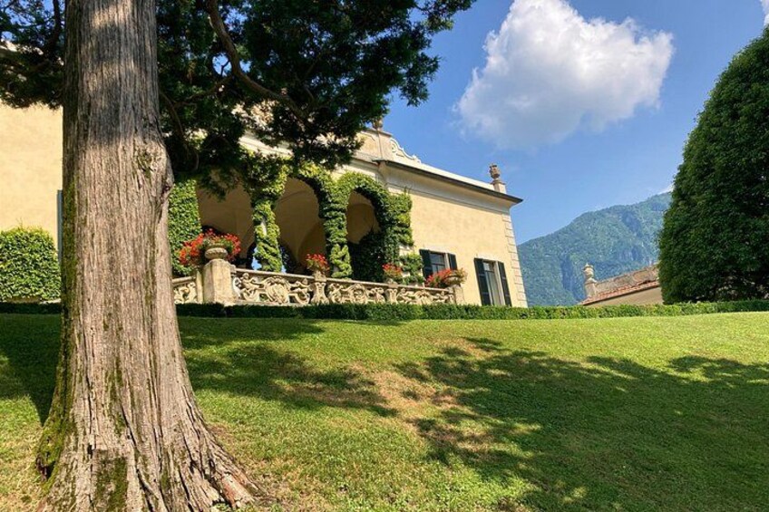 A building with arched windows, a large tree, and a mountain in the background. 4