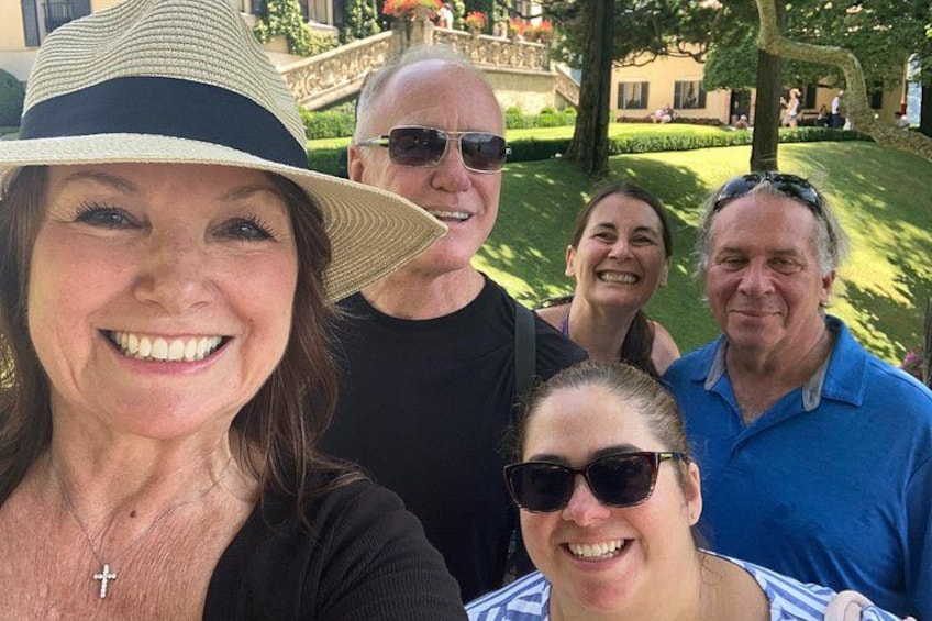 A group of people outdoors, with a well-maintained lawn and a building in the background. 3