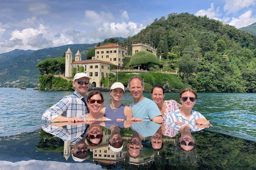 A group of people on a boat with a large building and greenery in the background. 5