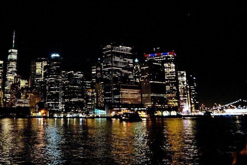 A nighttime city skyline with illuminated buildings reflected in the water. 5