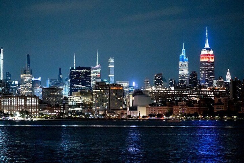A nighttime city skyline with illuminated buildings, including a prominent skyscraper with a spire. 3