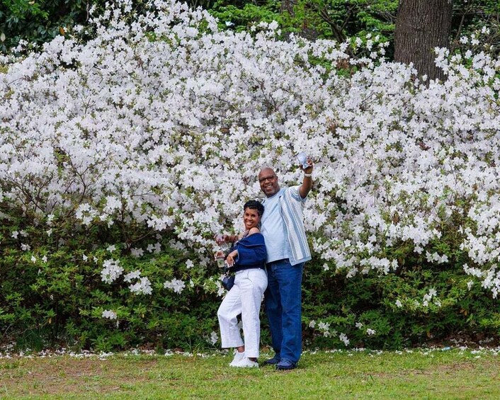 A man and a woman standing in front of a blooming white tree. 4