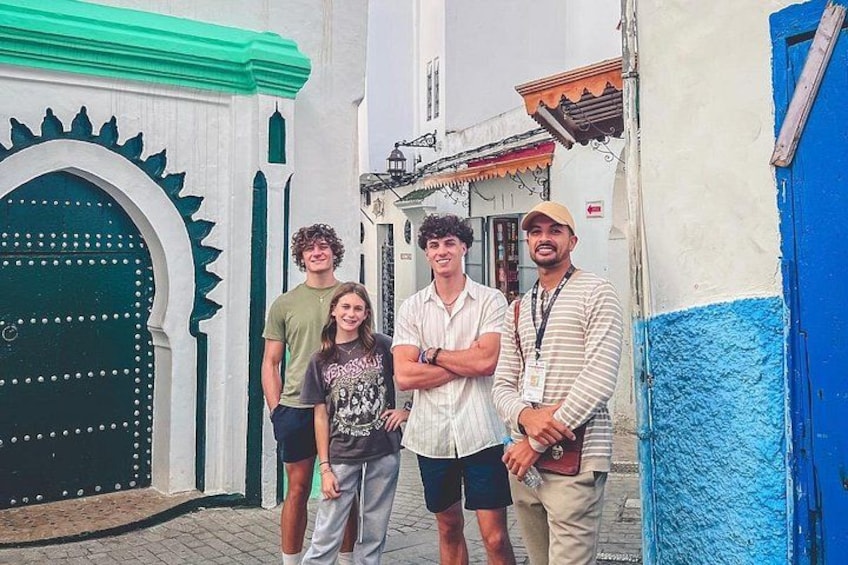 A group of people standing in front of a building with a green door and a blue wall. 5