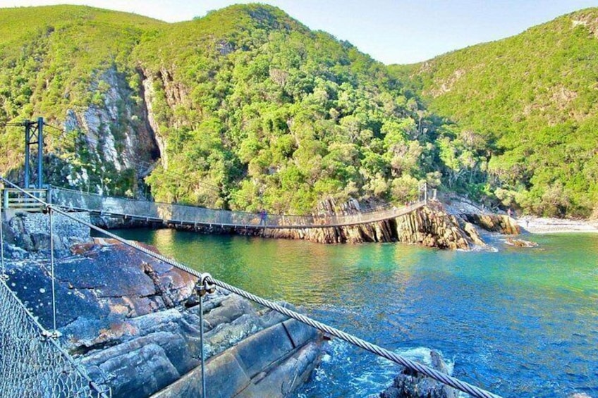 A suspension bridge over a body of water, surrounded by lush green hills. 4
