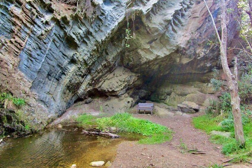 A rocky canyon with a bench, a stream, and a path. 3