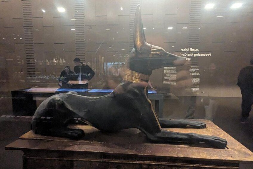 Een groot beeld van een liggende hond, met halsband, in een museum. 2