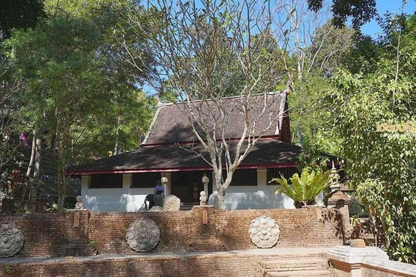 A traditional house with a tiled roof, surrounded by trees and a brick wall with decorative elements. 3