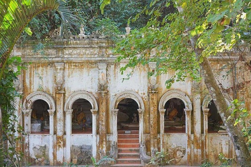 An old, weathered building with arched doorways and a staircase leading up to a door. 1