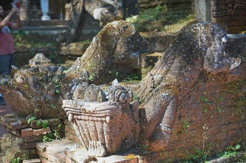 Ancient stone carvings of a lion's head, possibly part of a larger structure, with moss and vegetation growth. 5