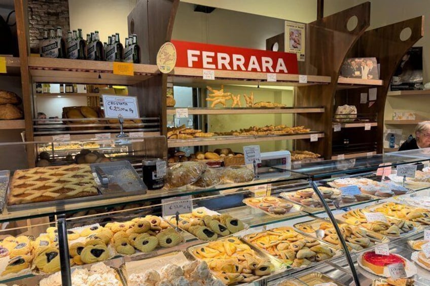 A bakery display with various baked goods and a Ferrara sign. 3