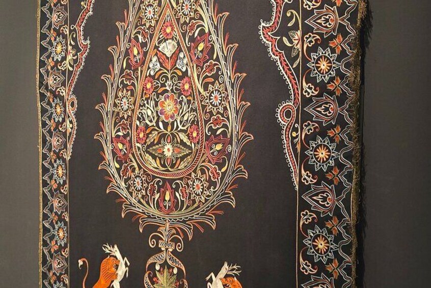 Ein detailliert besticktes Muster mit floralen und geometrischen Elementen auf dunklem Stoff. 4