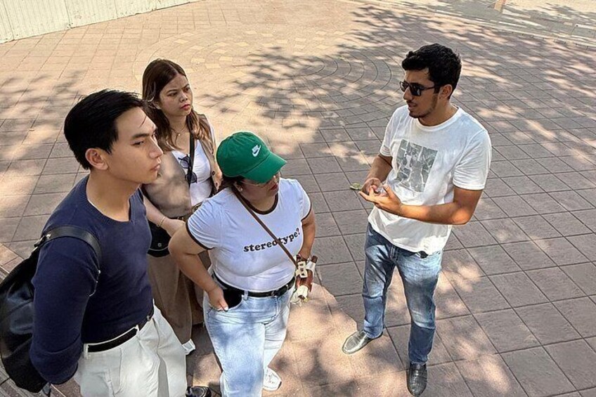 A group of people standing on a tiled pavement, engaged in conversation. 5