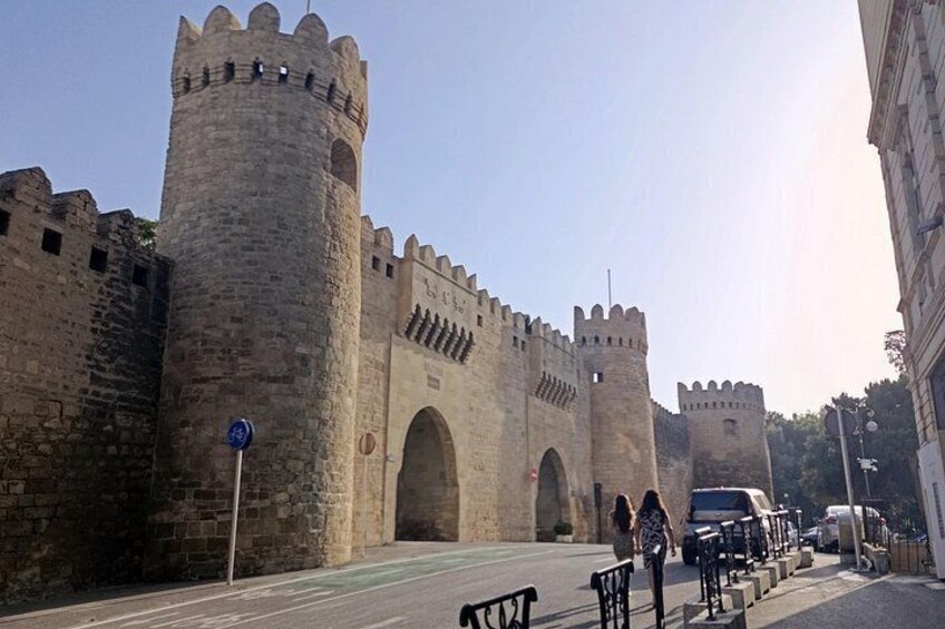 A historic stone castle with two prominent towers and a large arched gateway. 2