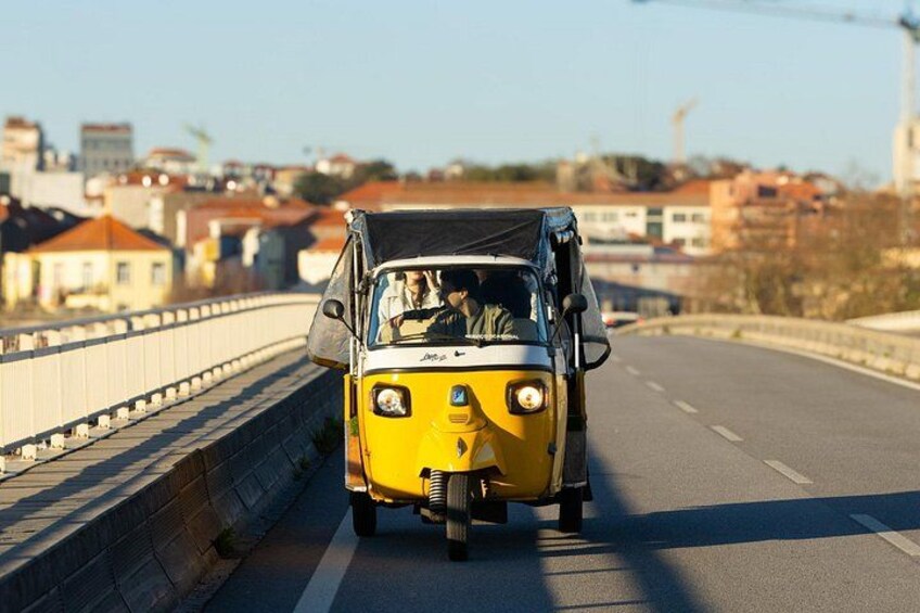 A yellow vehicle on a bridge with a cityscape in the background. 3