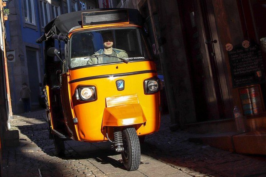 Un tuk-tuk amarillo estacionado en una calle empedrada. 2