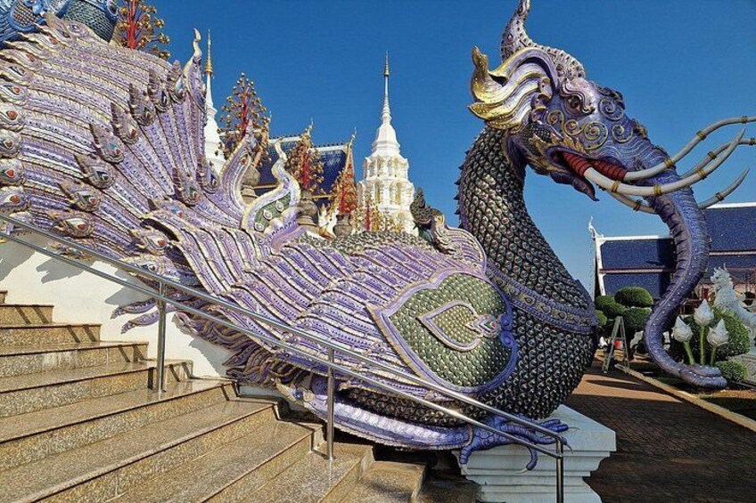 Une grande statue de dragon, richement décorée et ornée de motifs complexes, avec un temple en arrière-plan et un ciel bleu clair. 5
