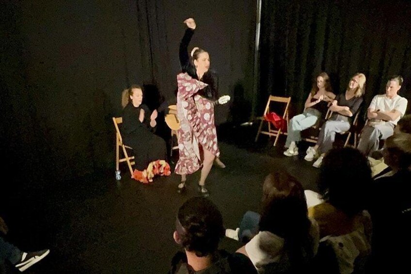 A person performing on stage with an audience seated in chairs. 2
