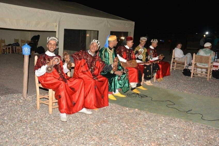 People in traditional attire seated outdoors at night. 2