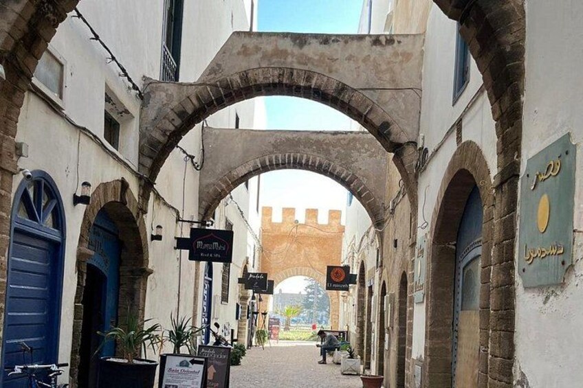 Eine enge Gasse mit gewölbten Steinbrücken, einer blauen Tür und einem Schild. 3