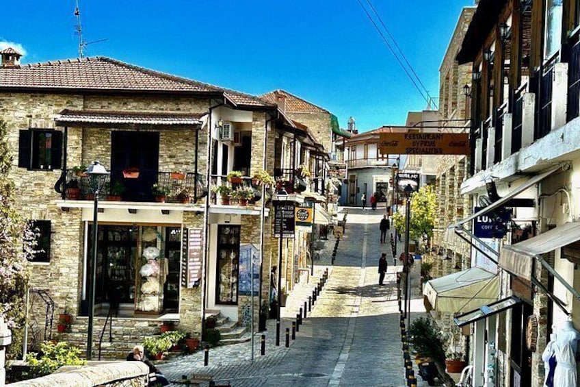A narrow street with stone buildings, a café, and a restaurant. 1