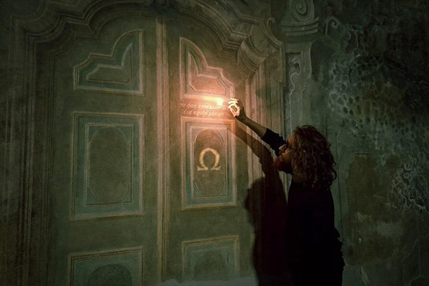 Una persona extiende la mano para tocar un símbolo brillante en una pared. 1