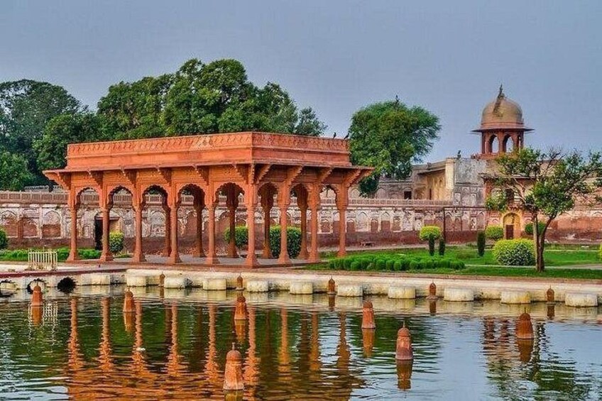 A pavilion with arches, a reflection in water, and a dome-shaped building in the background. 3