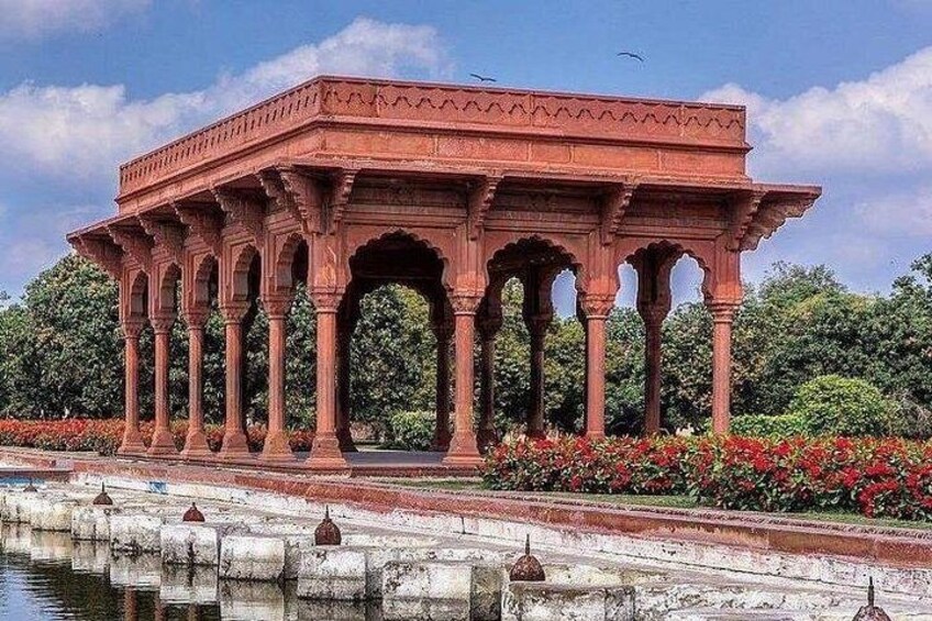 A red pavilion with arches, surrounded by water and red flowers. 2