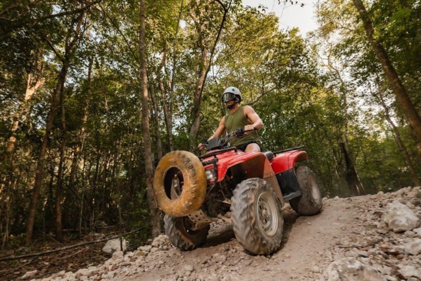 Eine Person fährt mit einem Quad auf einem steinigen Waldweg. 4