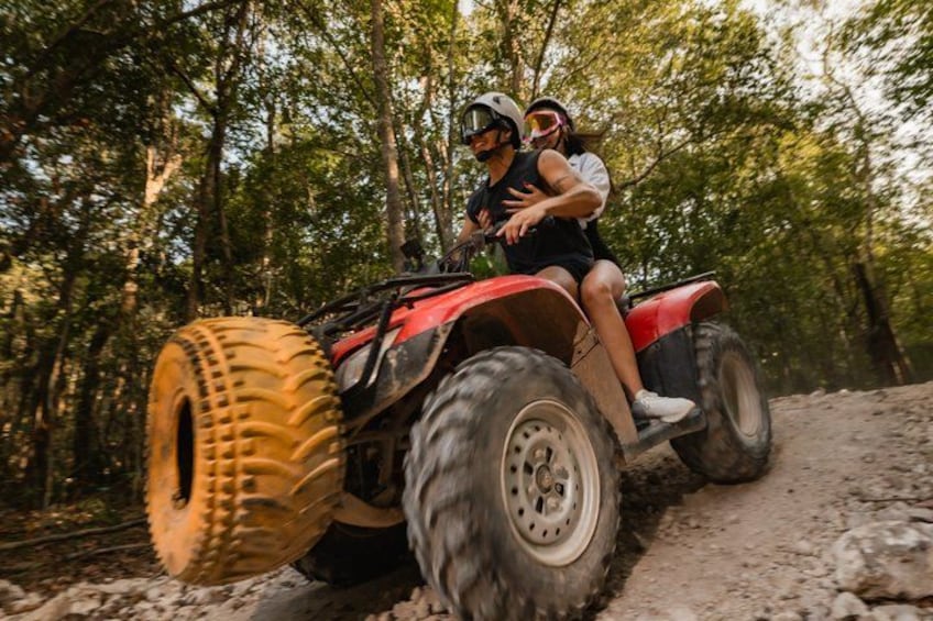 Eine Person fährt mit einem Quad auf einem Feldweg in einem bewaldeten Gebiet. 1