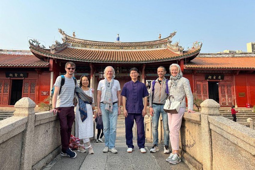 Een groep mensen staat voor een traditioneel Chinees gebouw met versierde architectuur. 4