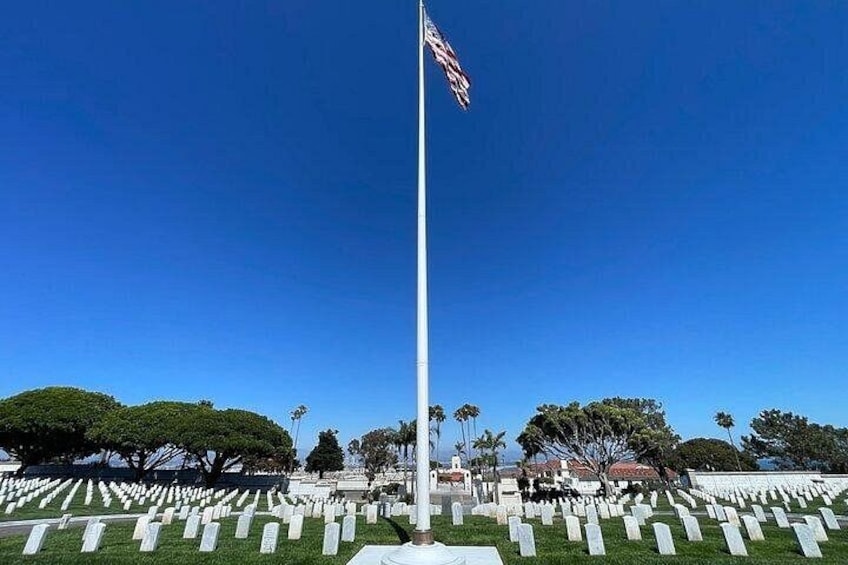 A flagpole with a flag, surrounded by a cemetery with headstones. 2