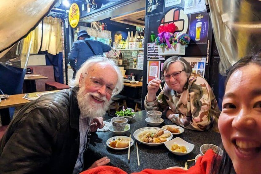 En grupp människor som äter på en restaurang, och på bordet står olika rätter. 3