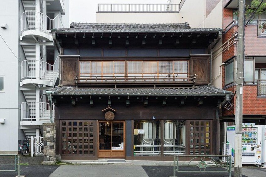 A traditional Japanese building with a wooden facade, a balcony, and a vending machine on the right. 2