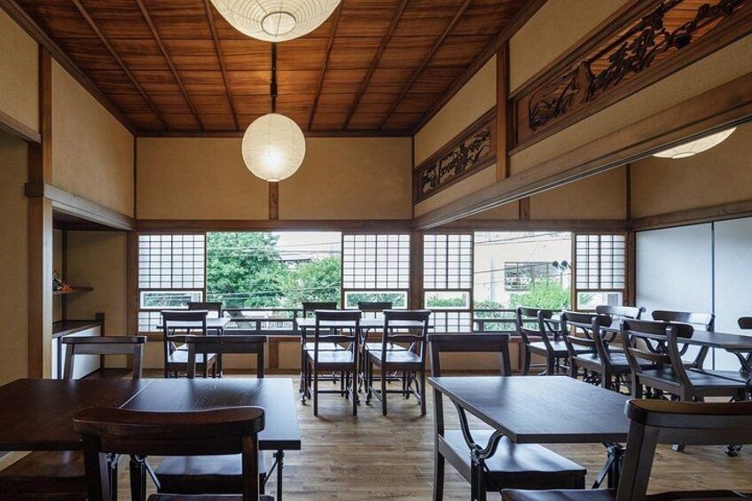 A traditional Japanese restaurant with wooden tables and chairs, large windows, and a hanging light fixture. 5