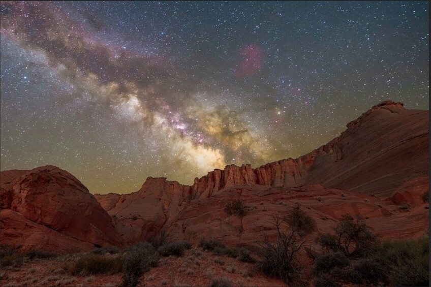A starry night sky over a desert landscape with red rock formations. 2