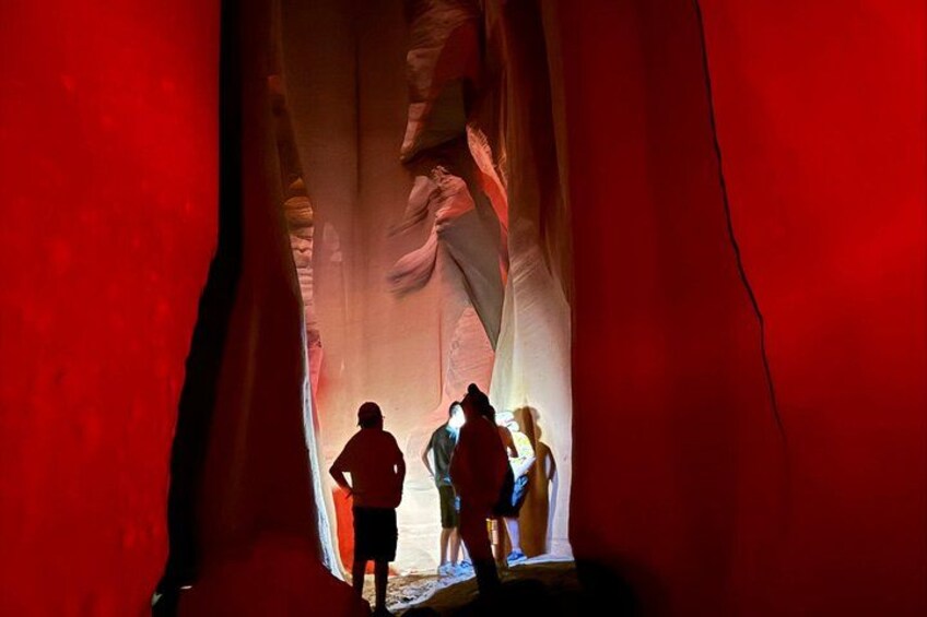 A group of people inside a red-lit cave with rock formations. 4