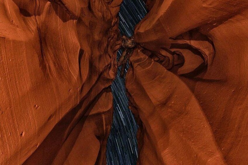 A close-up of a canyon with reddish-brown rock formations and a narrow blue water channel. 3