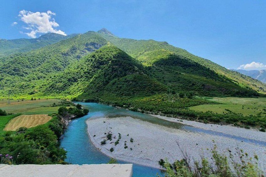 A river winding through a valley with lush green hills and a mountain in the background. 2