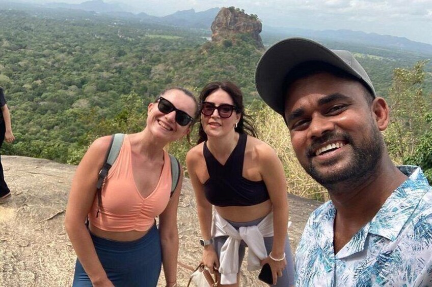 Three people standing on a rocky outcrop with a mountainous landscape in the background. 5