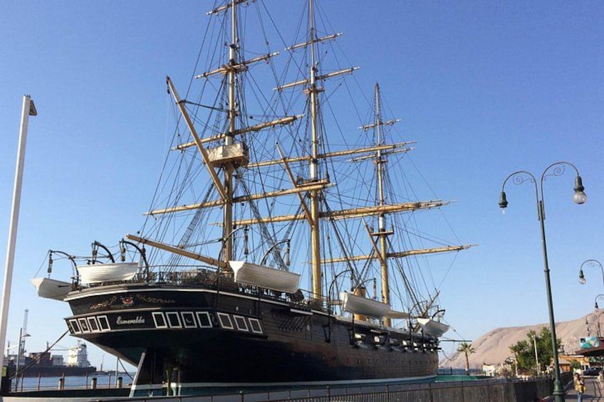 Un grand voilier était amarré dans un port, sous un ciel dégagé, avec des montagnes en toile de fond. 5