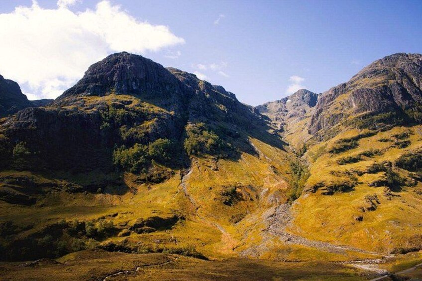 Een bergachtig landschap met een vallei, rotsformaties en schaarse begroeiing. 3
