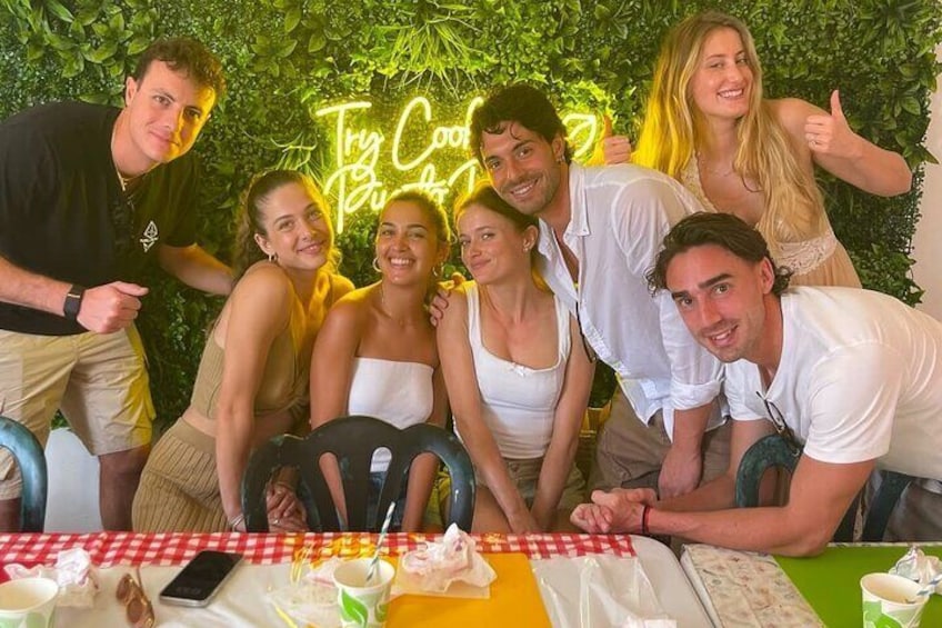 A group of people posing at a table with a neon sign in the background. 2
