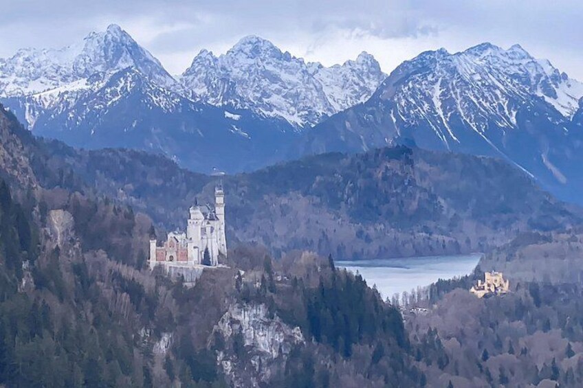 Un castillo rodeado de montañas y un lago. 3